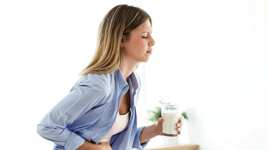 How do your genes affect lactose intolerance? A woman struggles to digest a glass of milk.