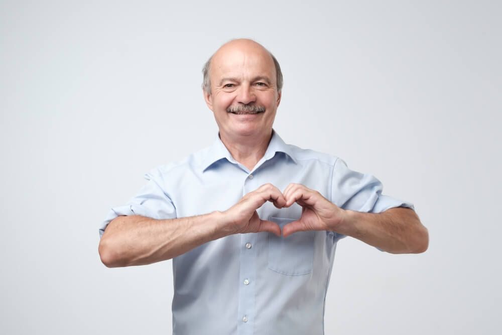 An elderly man emphasizes the heart's significance through hand gestures.