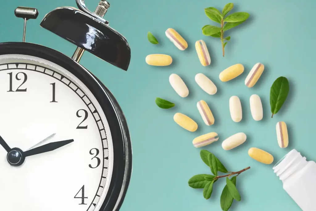 Vitamins pills spilled out from a bottle. There's an alarm clock next to it. The picture is indicative of "how long does it take for vitamins to work?"